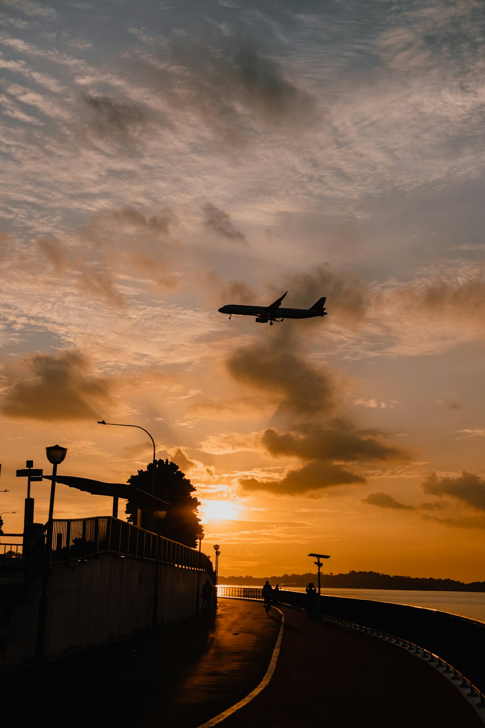 a plane is flying over a bridge at sunset