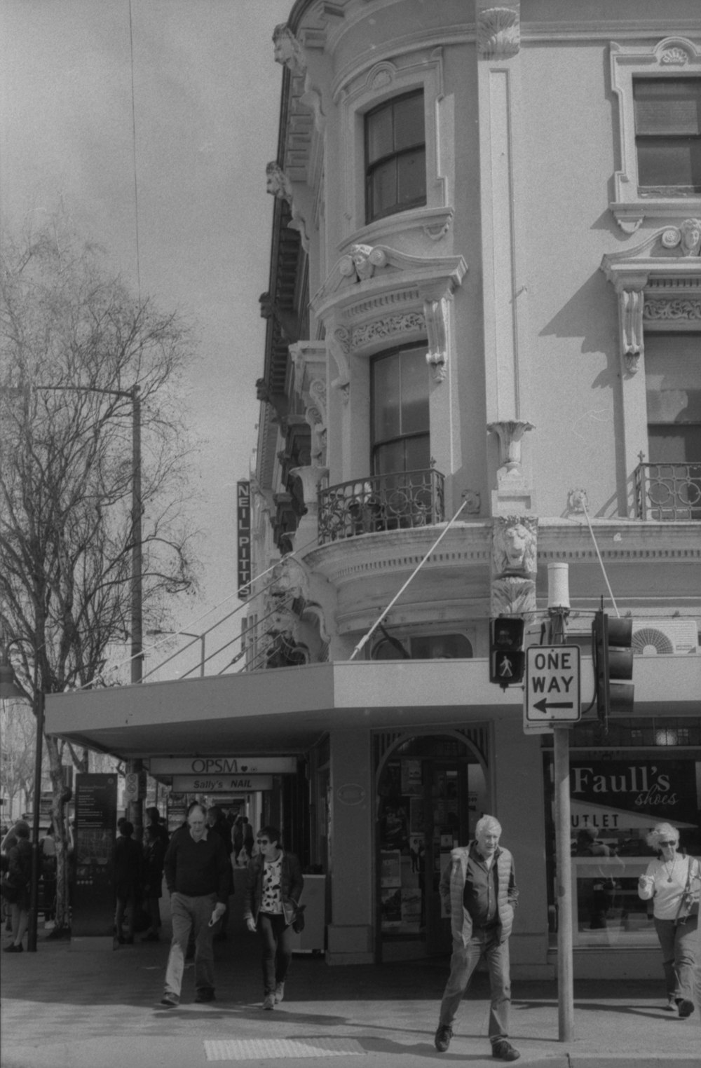 a black and white photo of people crossing the street