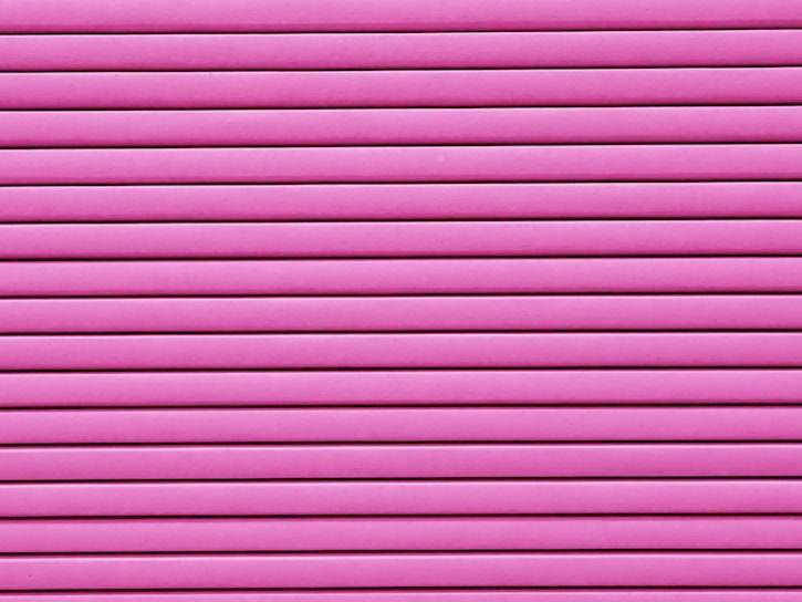 Horizontal pink blinds or slats cover the entire frame, creating a pattern of alternating light and shadow.