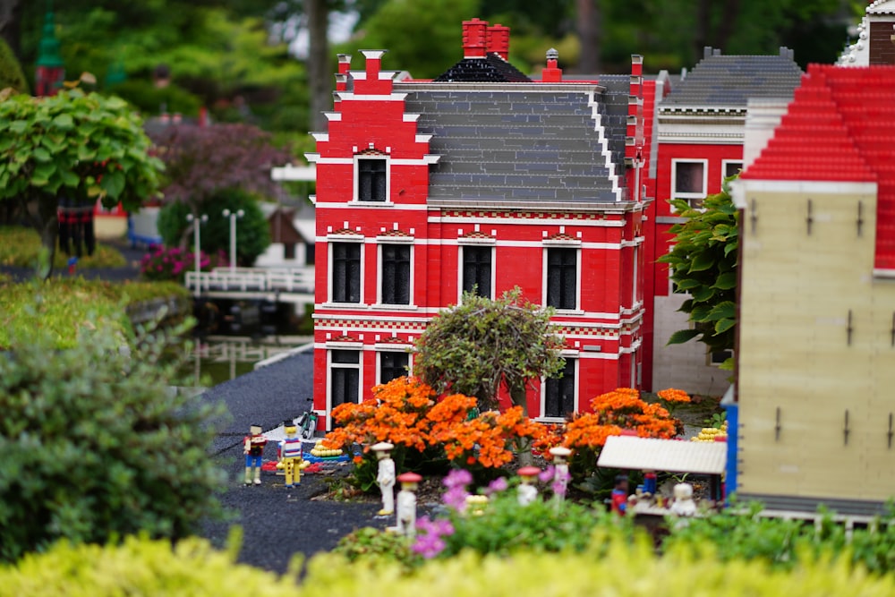 a model of a red house surrounded by flowers