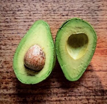 an avocado cut in half on a wooden table