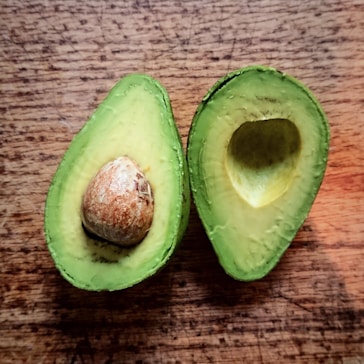 an avocado cut in half on a wooden table