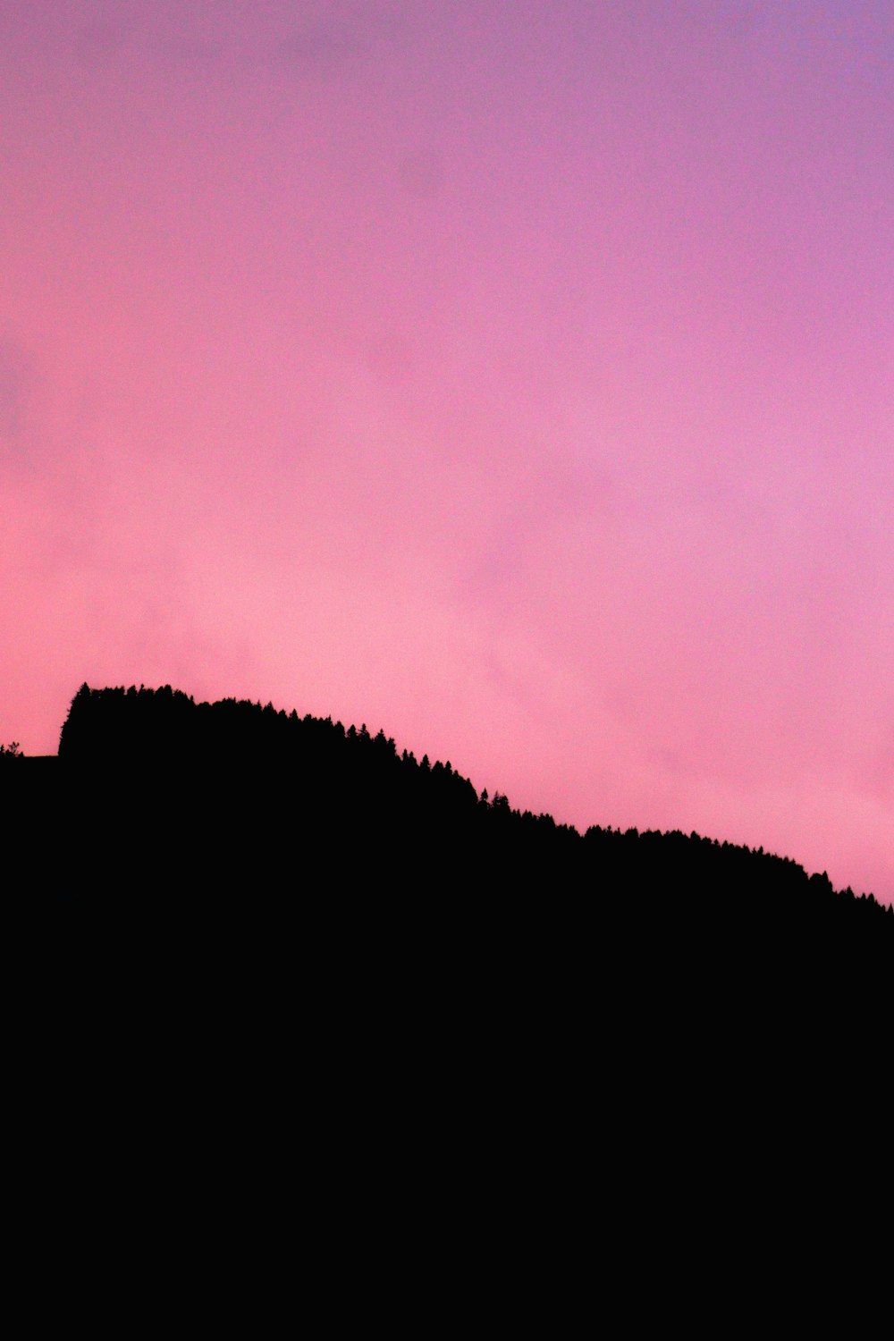 a silhouette of a person standing on top of a hill