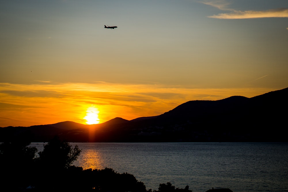 Ein Flugzeug, das bei Sonnenuntergang über ein Gewässer fliegt