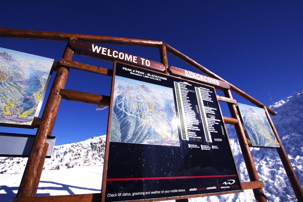 a welcome sign in front of a snowy mountain