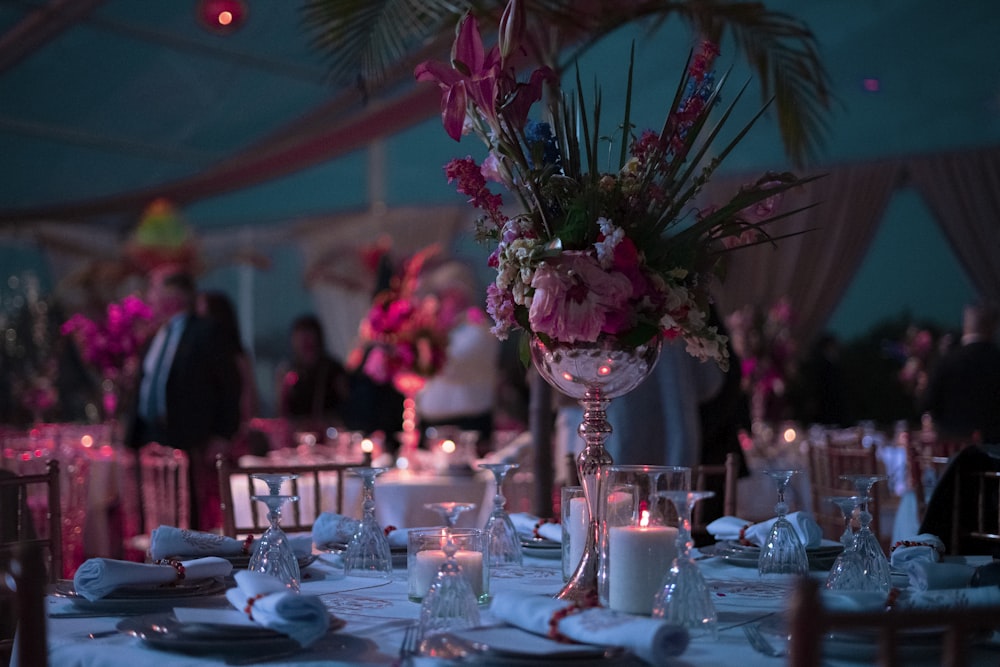 a table with a vase of flowers and candles on it