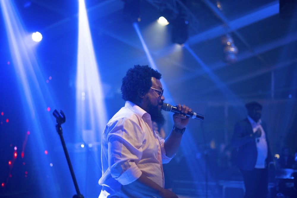 a man singing into a microphone on stage