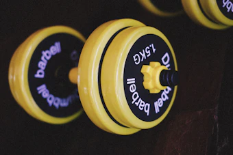 a row of yellow and black dumbbells on a wall