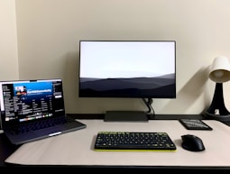 a desk with a laptop, keyboard, mouse and monitor