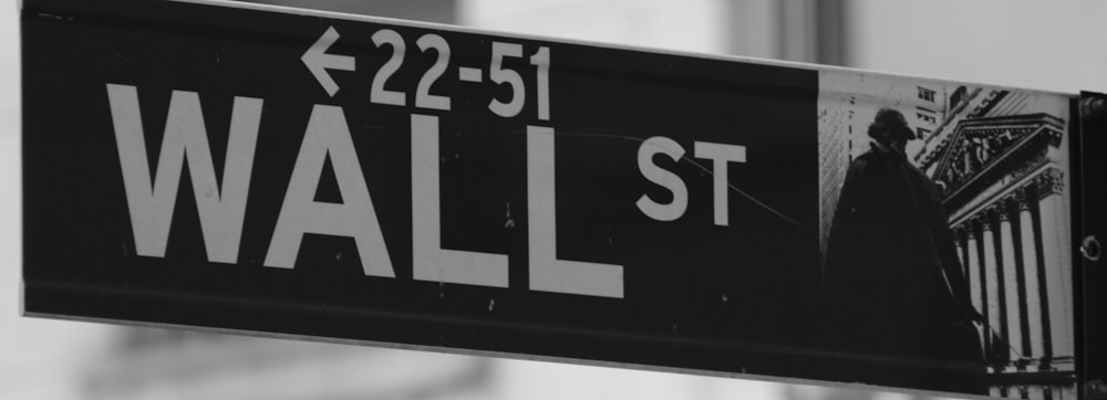 a black and white photo of a wall street sign