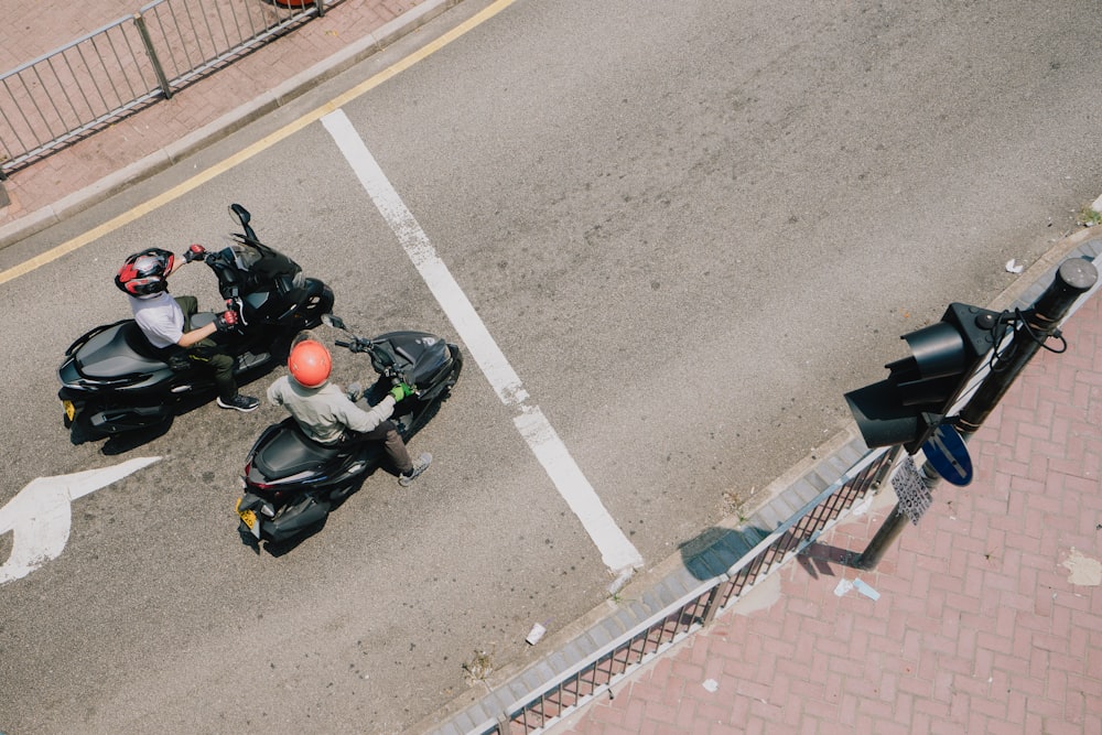 two motorcyclists on a city street near a traffic light