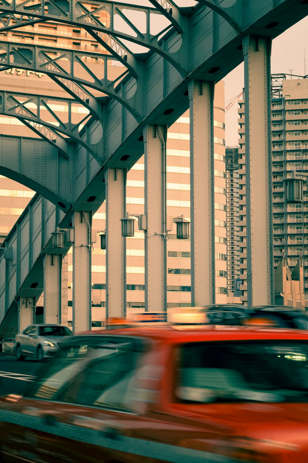 a red car driving down a street next to tall buildings