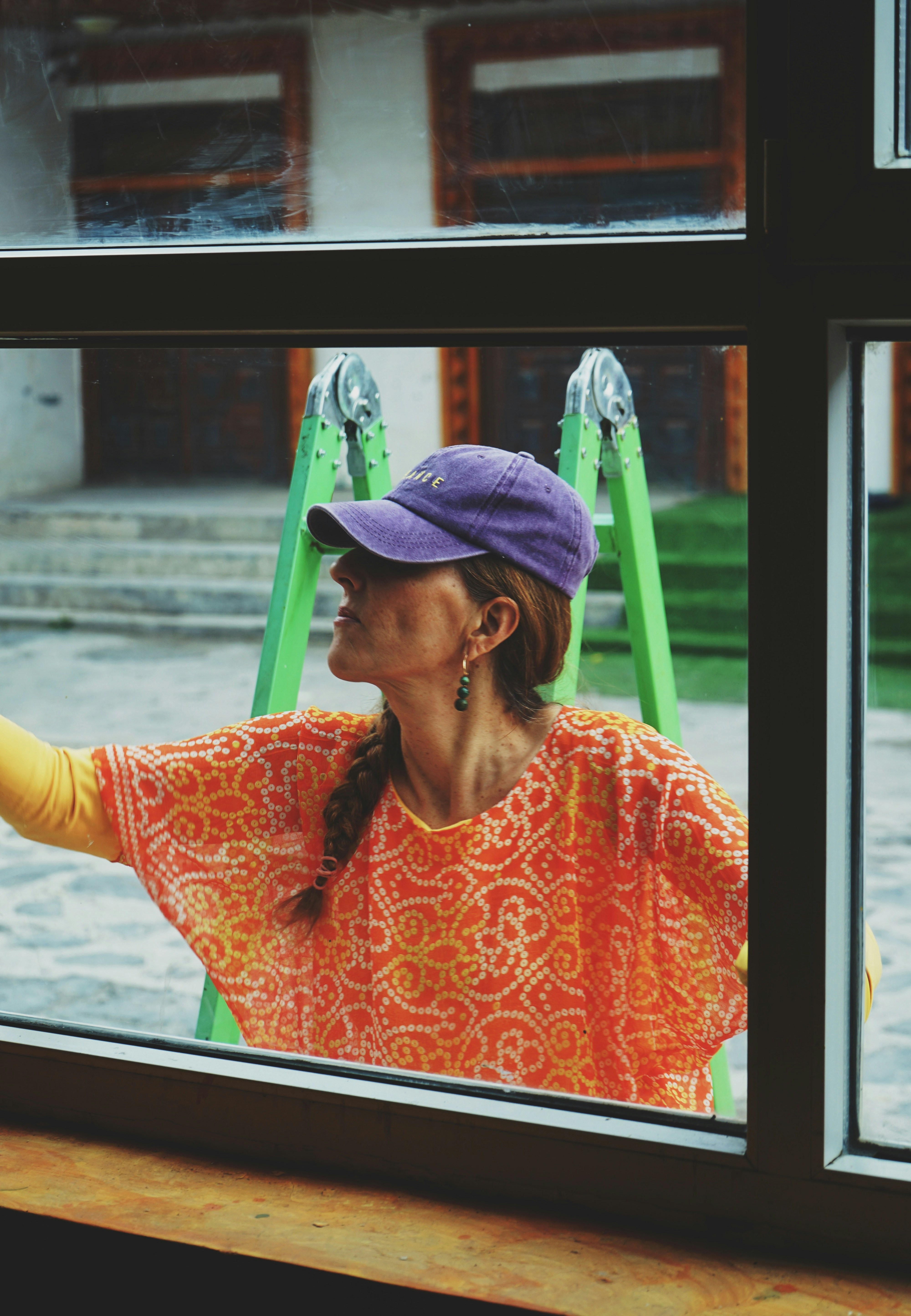 a woman looking out a window with a purple hat on