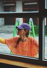 a woman looking out a window with a purple hat on