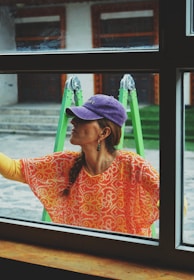 a woman looking out a window with a purple hat on
