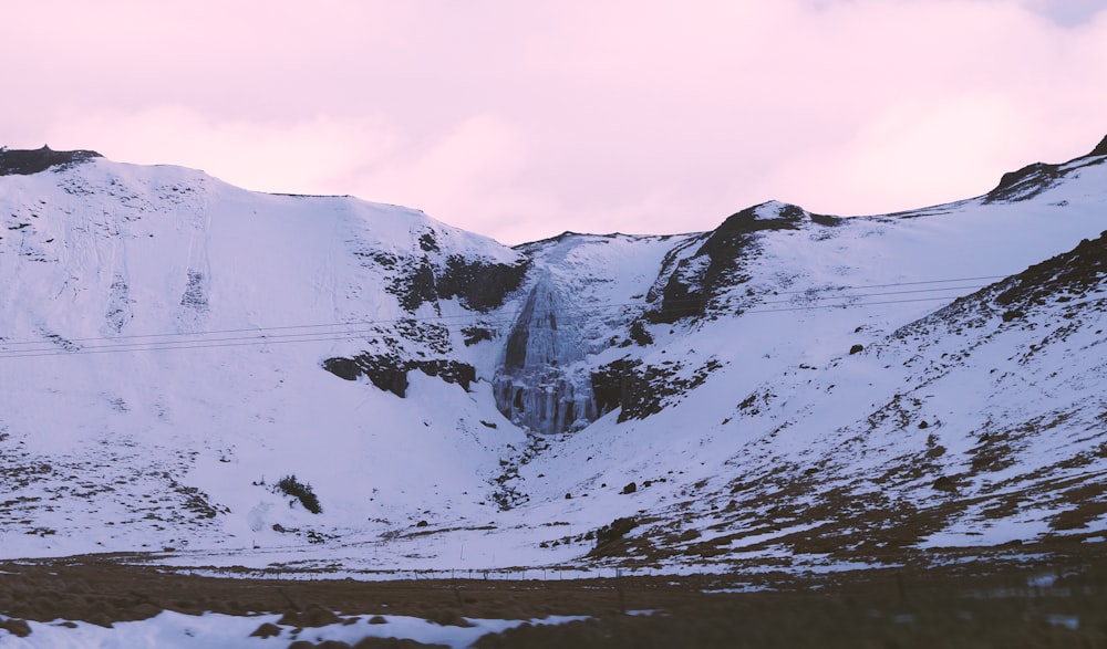 a snow covered mountain with a waterfall in the distance