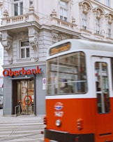 a red and white bus driving past a bank