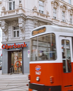 a red and white bus driving past a bank