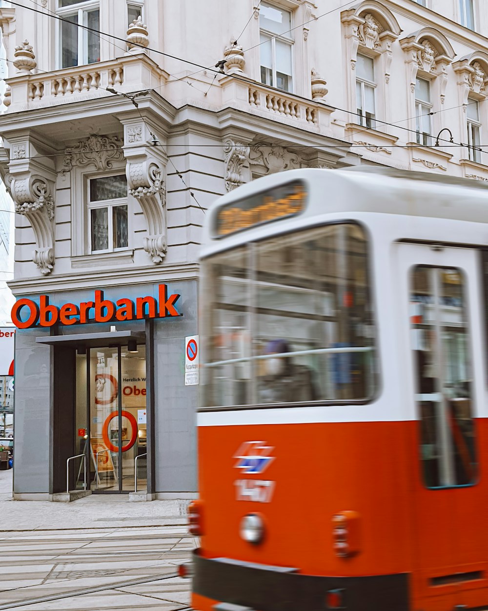 a red and white bus driving past a bank