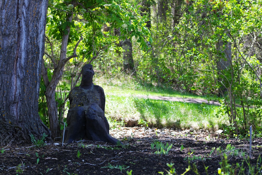 a statue sitting in the middle of a forest