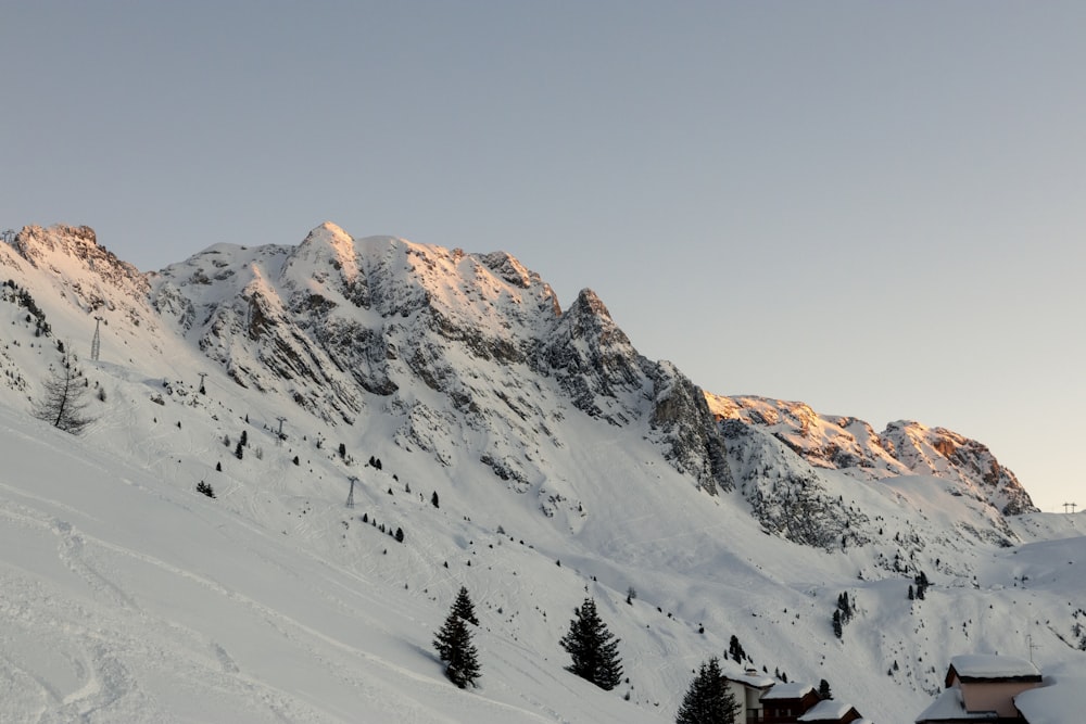 a snow covered mountain with a house in the foreground