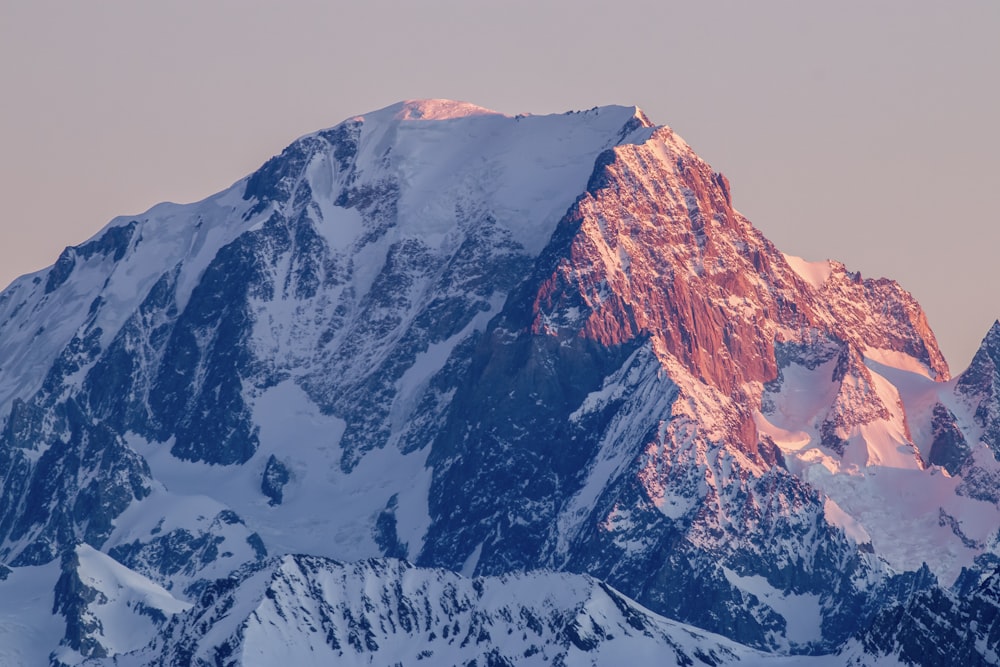 a large mountain covered in snow at sunset