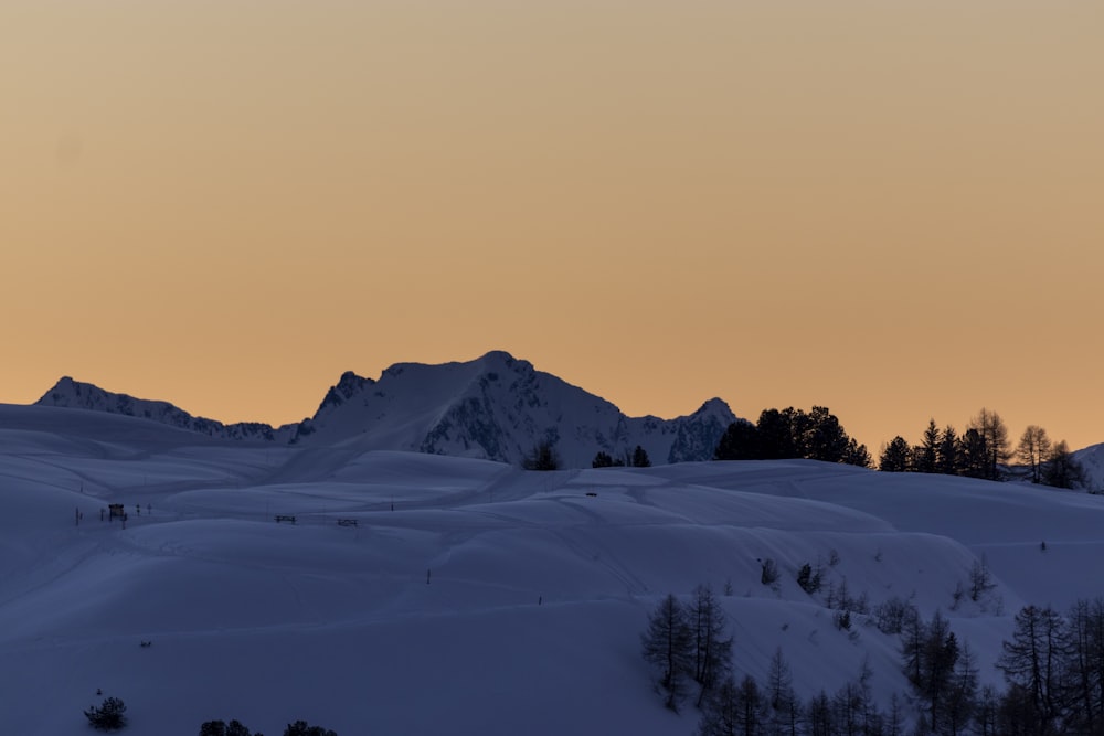 a mountain covered in snow with a sunset in the background