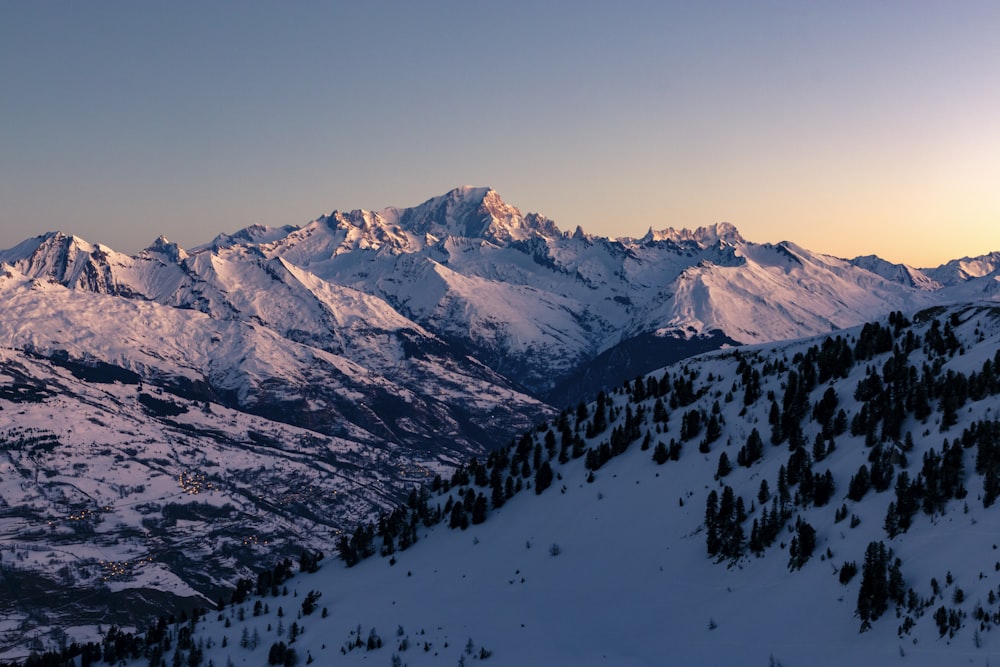 a view of a snowy mountain range at sunset