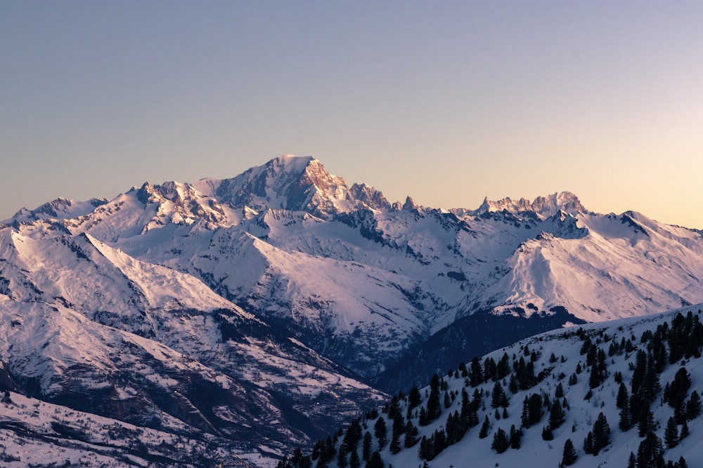 a mountain range covered in snow at sunset