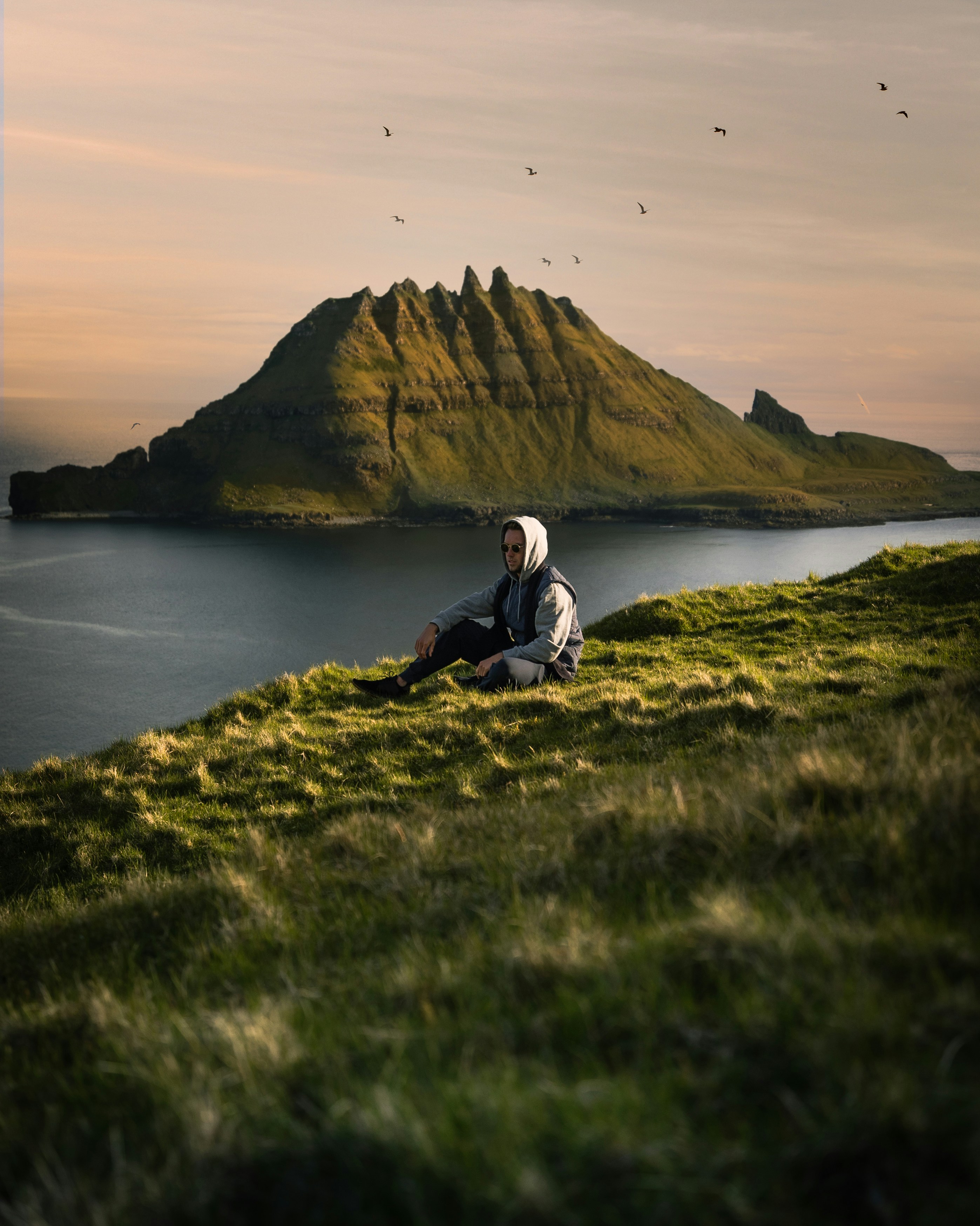 a man sitting on top of a lush green hillside