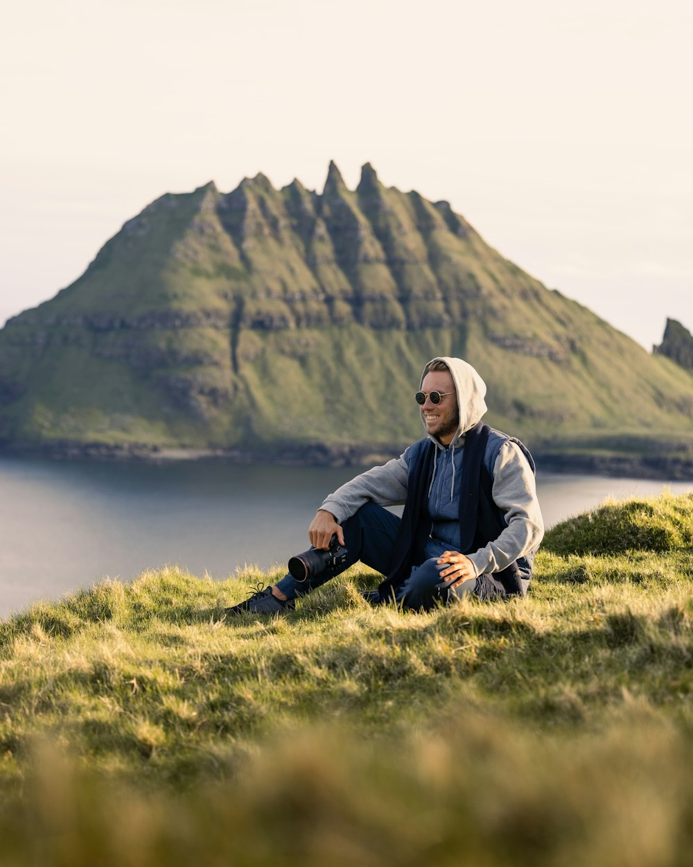 a man sitting on top of a lush green hillside