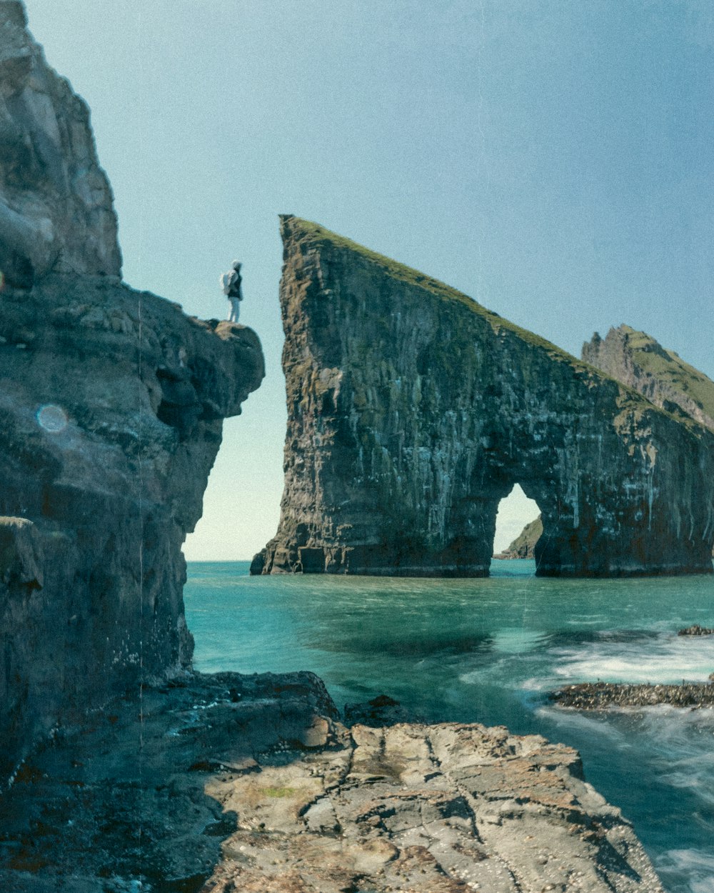 a man standing on top of a cliff next to the ocean