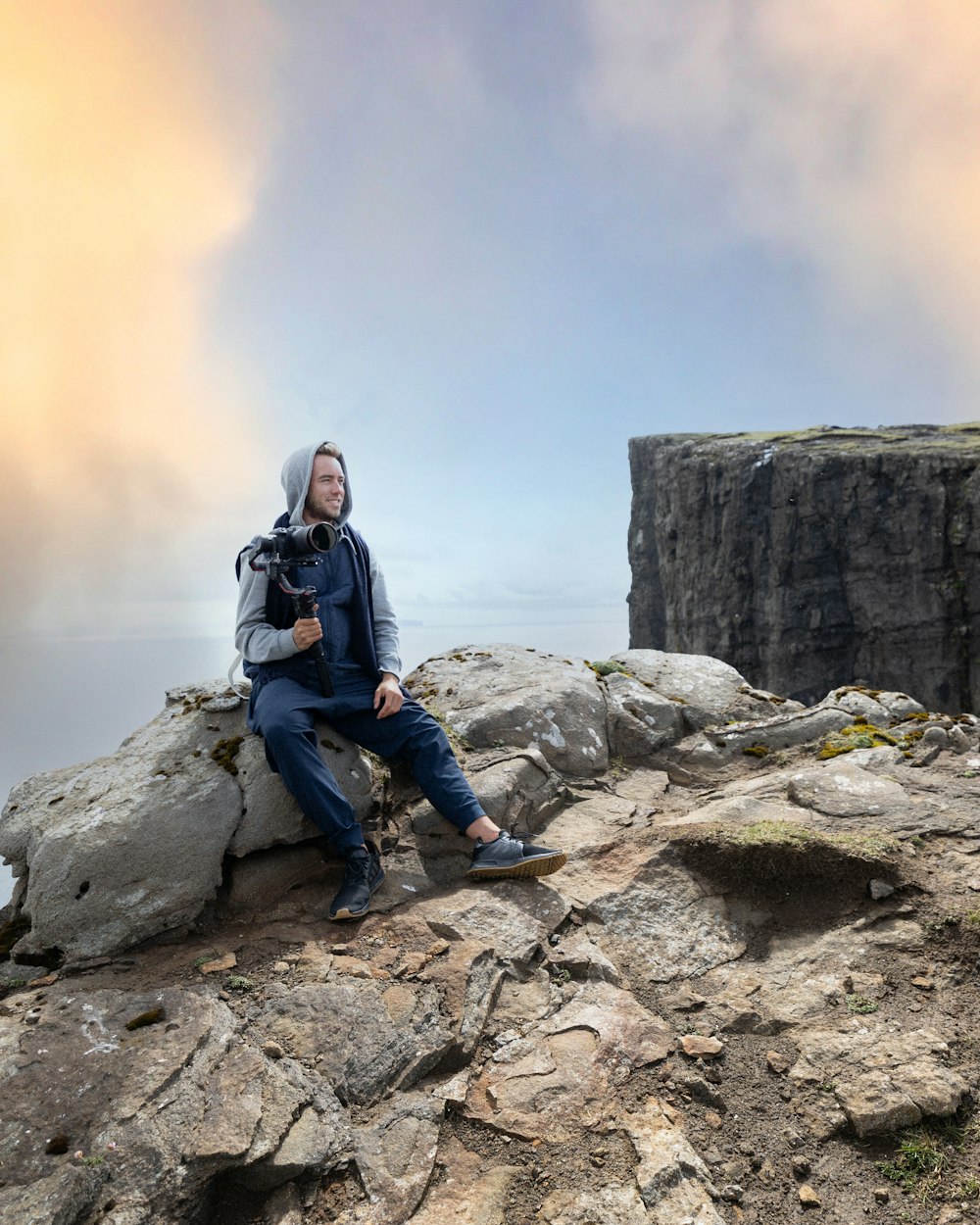 Un hombre sentado en la cima de un acantilado rocoso