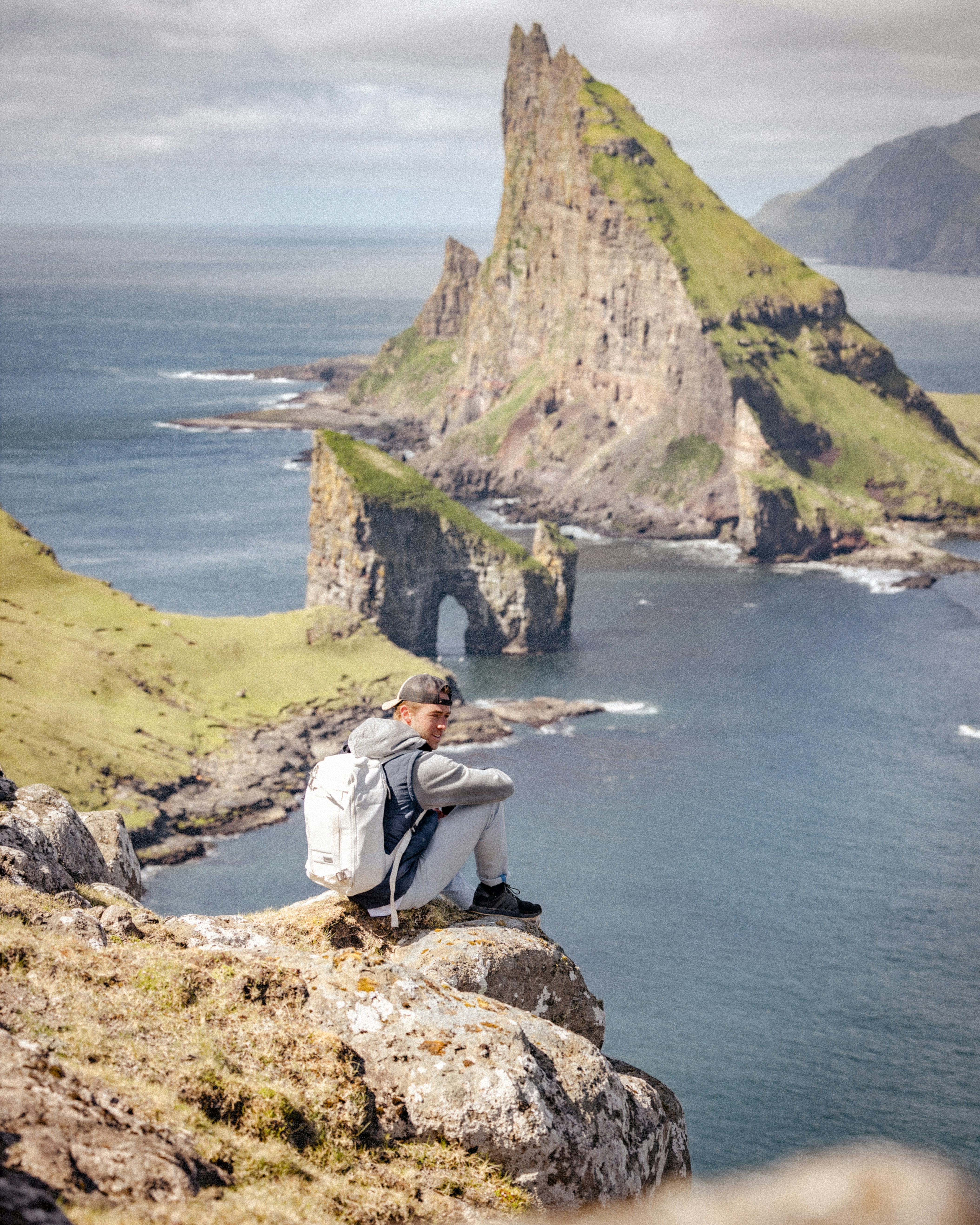 a man sitting on top of a rock next to a body of water