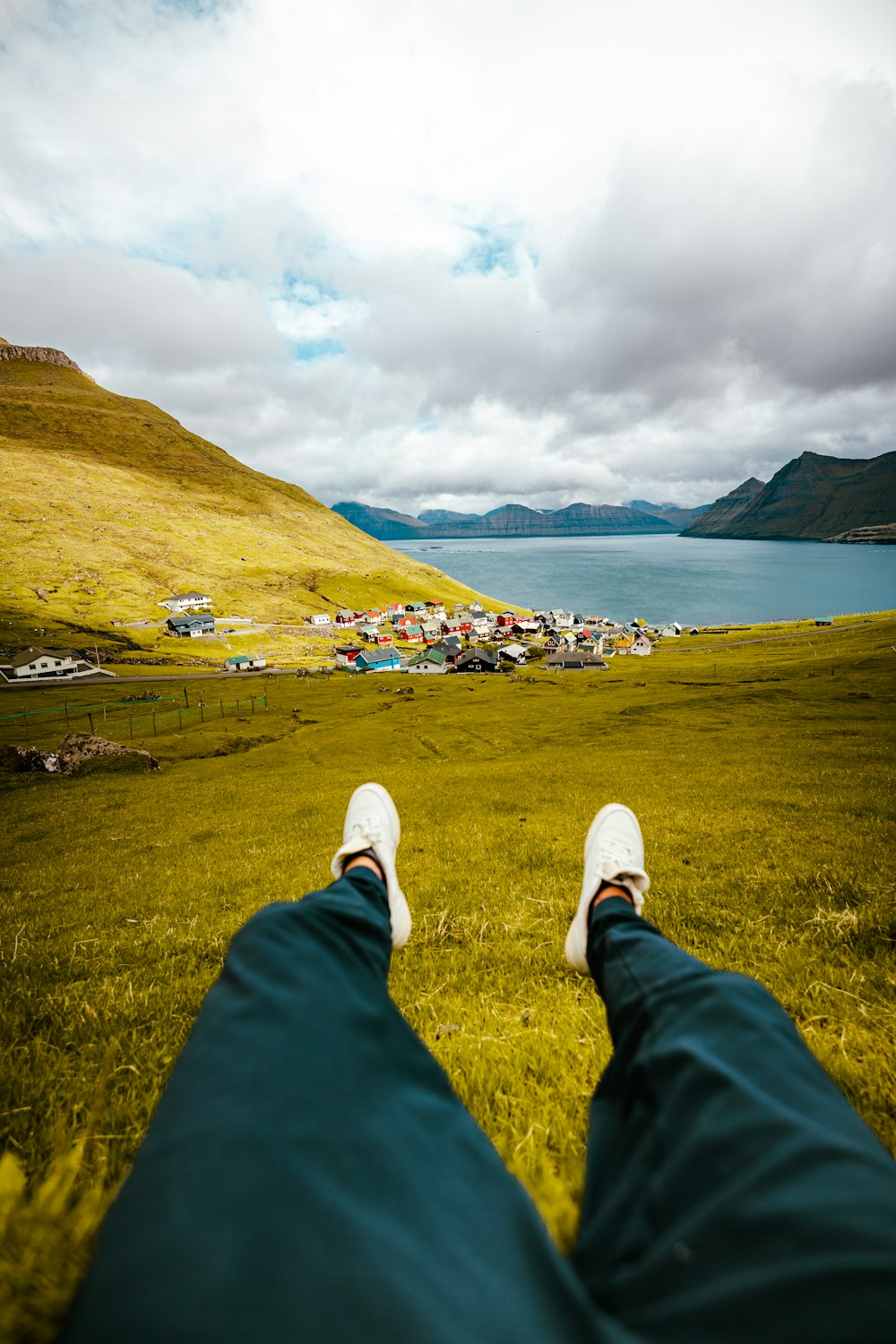 a person's feet in the grass with a lake in the background