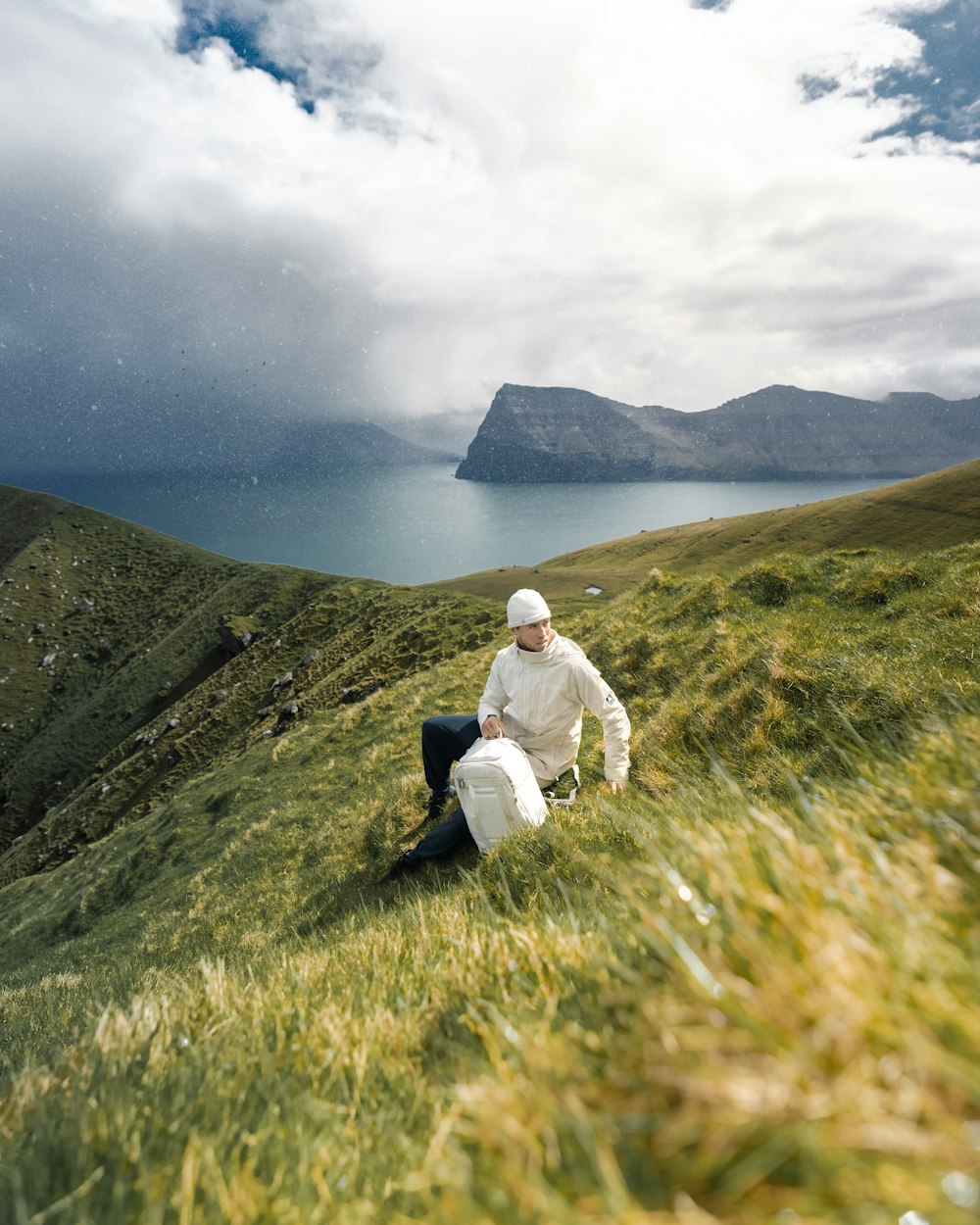 a man sitting on top of a lush green hillside