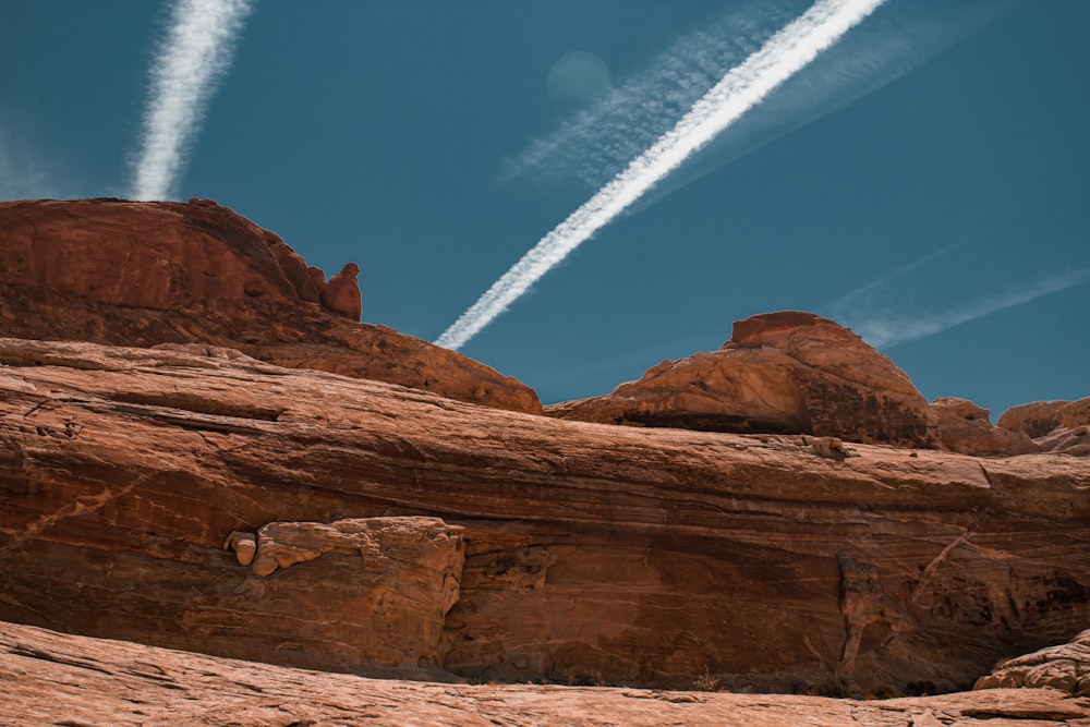 two airplanes flying over a rocky landscape under a blue sky