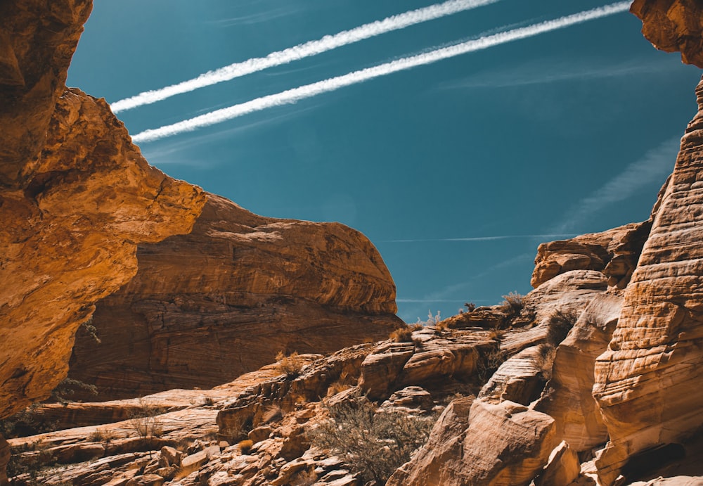 a plane flying in the sky over some rocks