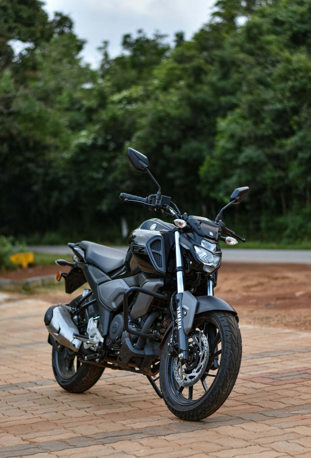 Una motocicleta negra estacionada en un camino de ladrillos