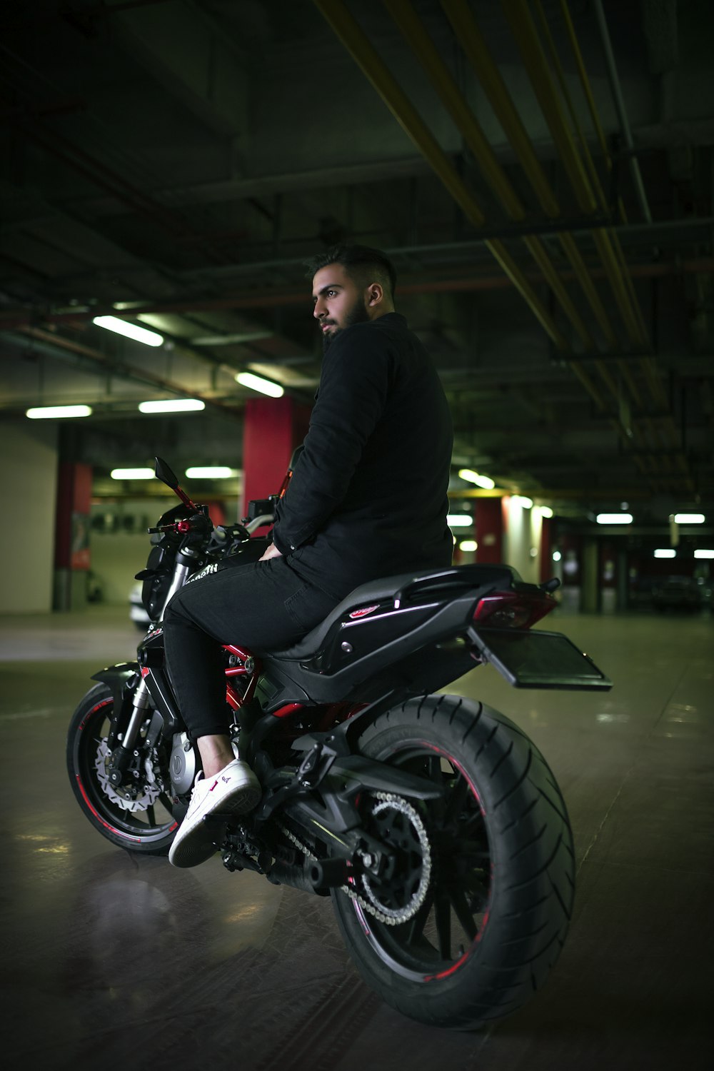 a man sitting on a motorcycle in a parking garage