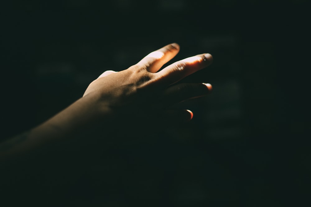 a person holding their hand out in the dark