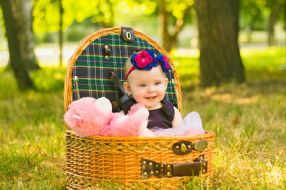 a baby sitting in a basket in the grass