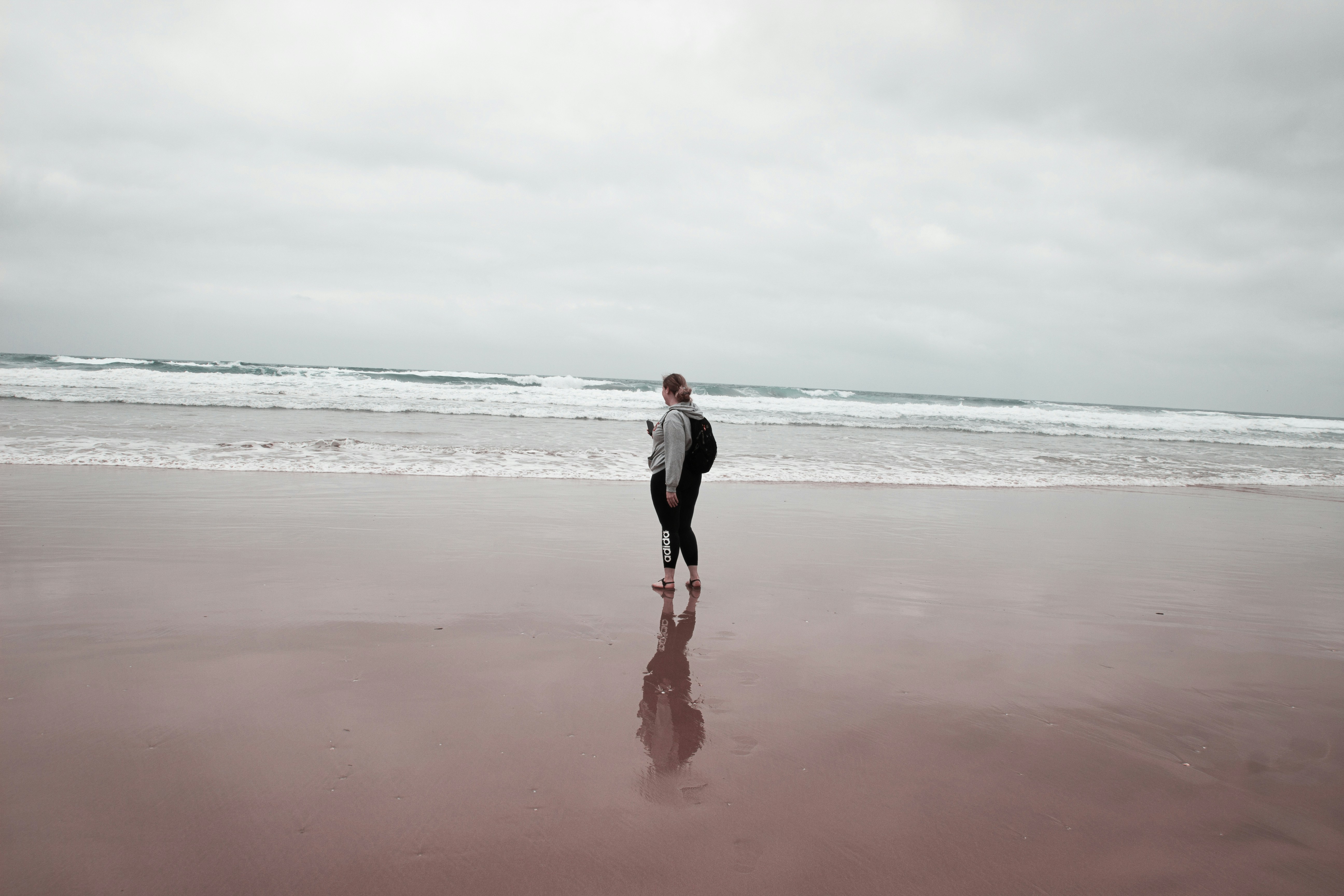 a man standing on a beach next to the ocean, 
