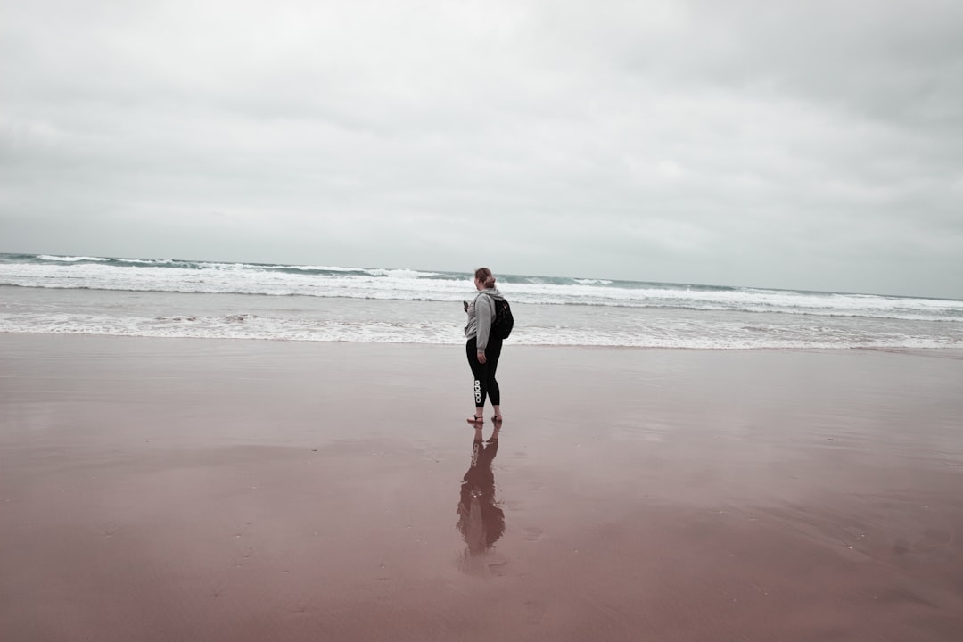 a man standing on a beach next to the ocean,