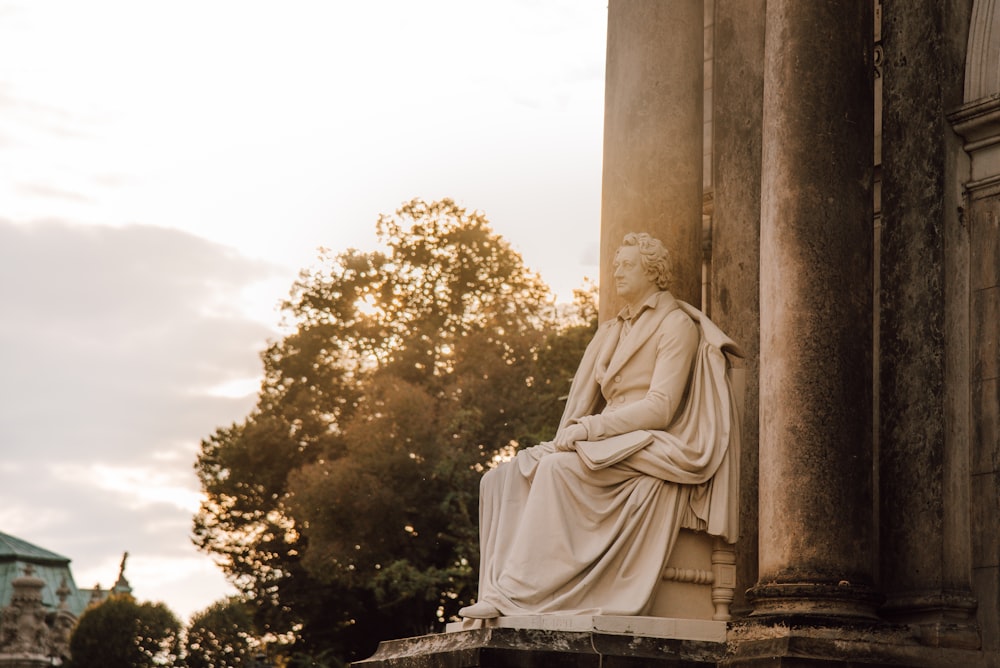 a statue of a man sitting on top of a pillar