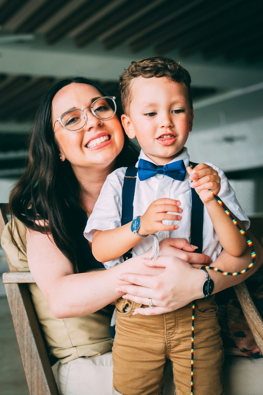a woman holding a small boy wearing a bow tie