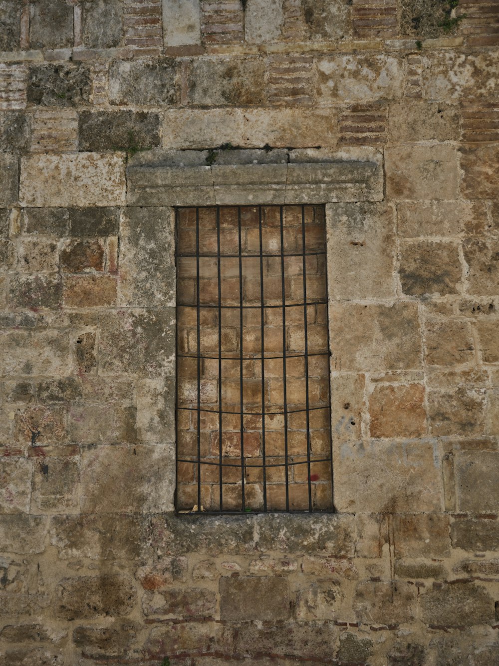 a brick wall with a window and bars on it