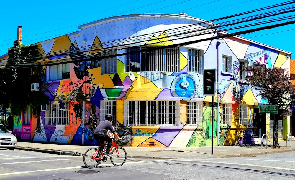a man riding a bike past a colorful building