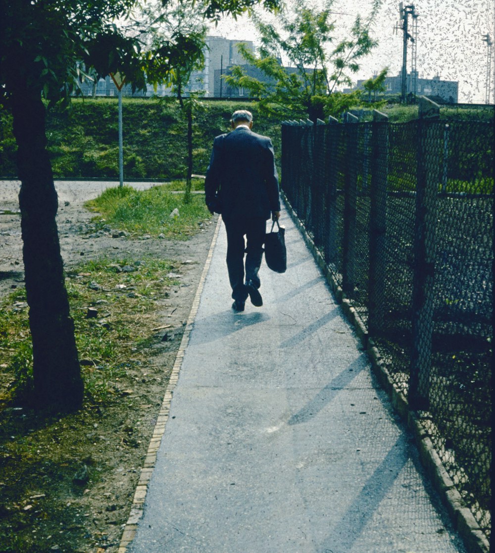 a man walking down a sidewalk carrying a bag