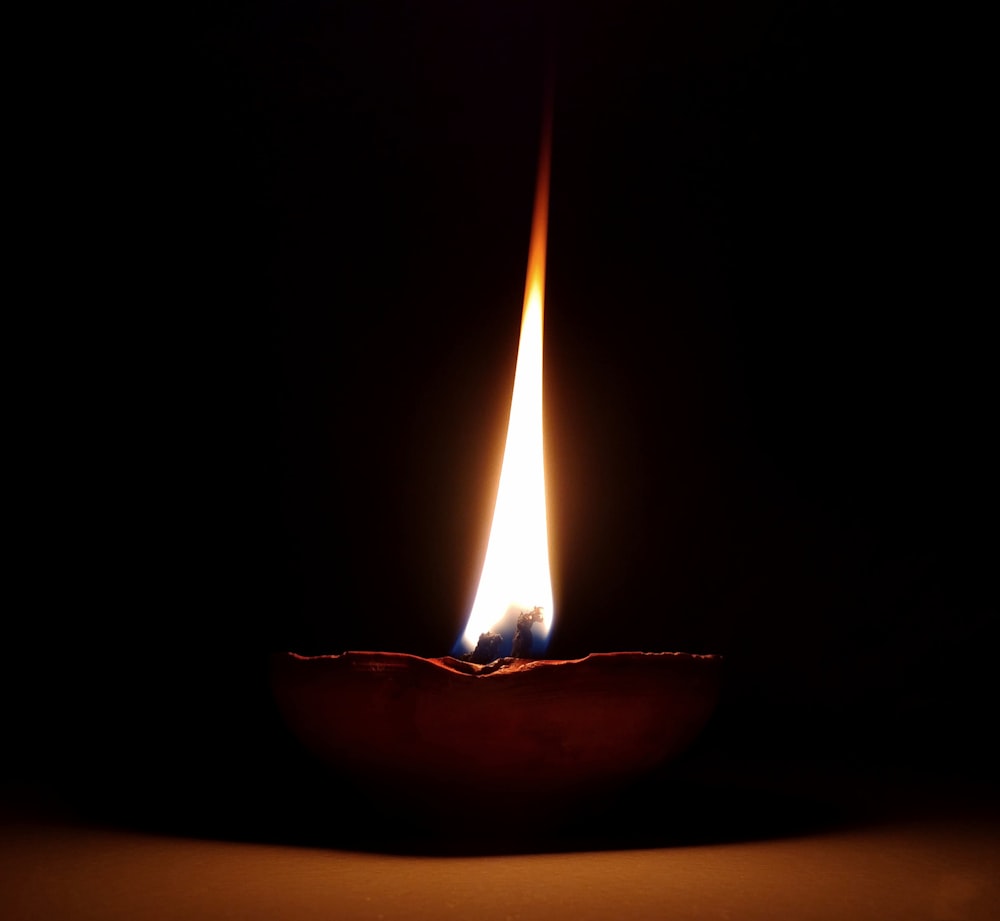 a lit candle in the dark on a table